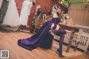 A woman in a purple dress sitting on a wooden chair.