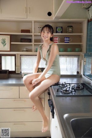 A woman laying on top of a kitchen counter next to a toaster.