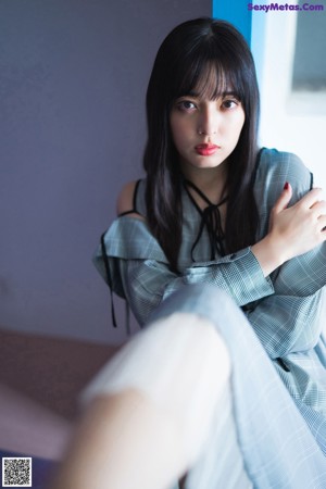 A woman laying on top of a blue couch.