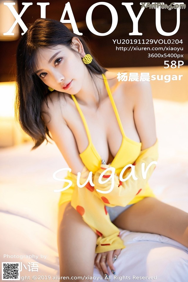 A woman in a yellow bikini sitting on a bed.