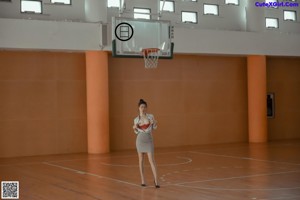 A woman in a school uniform is standing in a classroom.