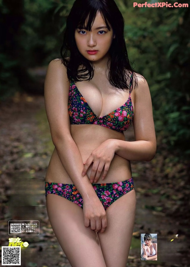 A woman in a bikini posing in the woods.