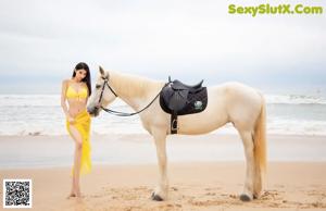 A woman in a white dress riding a horse on the beach.