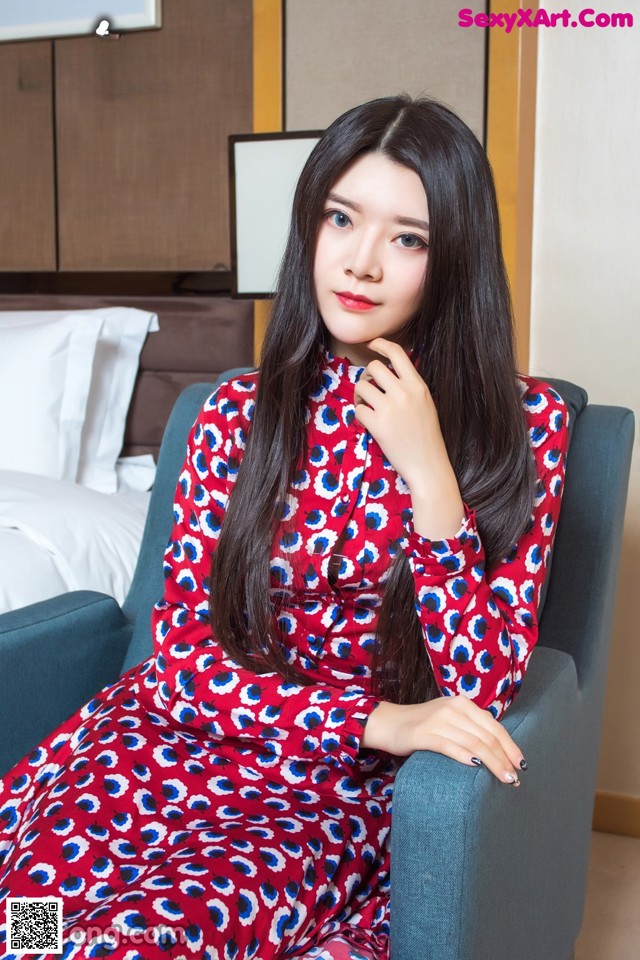 A woman in a red and blue dress sitting on a blue chair.