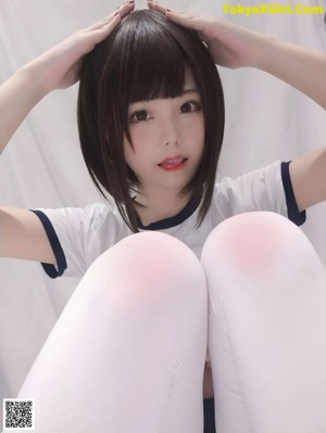 A woman in a white shirt and black panties is sitting on a bed.
