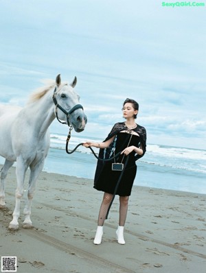 A woman laying on the sand in a black sweater.