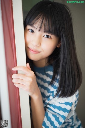 A young woman sitting in front of a green window.