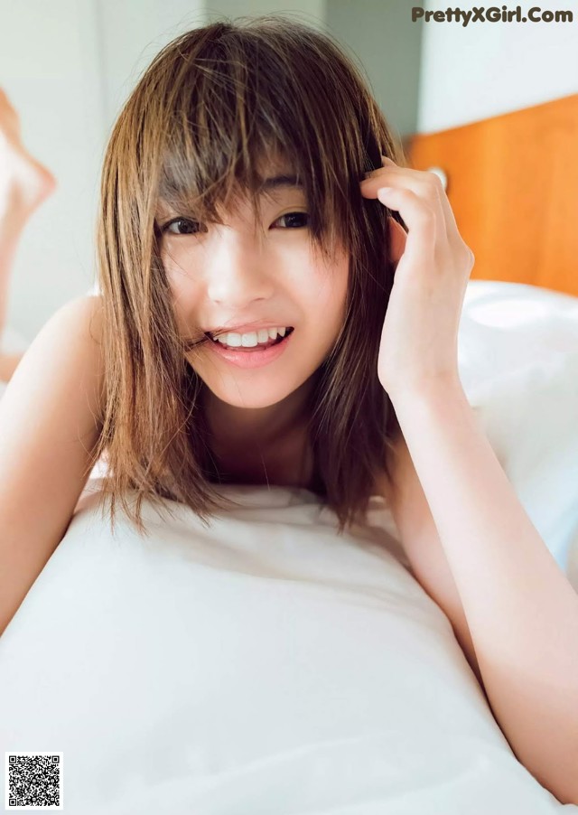 A woman laying on top of a bed smiling.