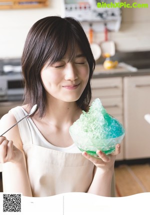 A woman in a kitchen preparing food with a machine.