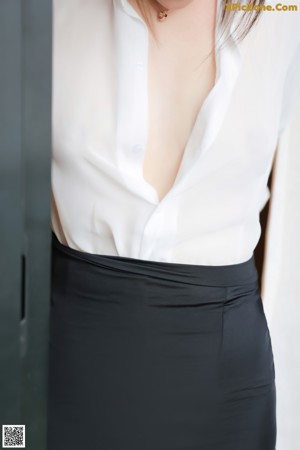 A woman in a white shirt and black skirt sitting on a couch.