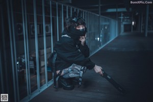 A woman in a black jacket and mask walking down a walkway.