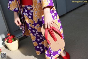 A woman wearing a purple and red kimono and a red scarf.