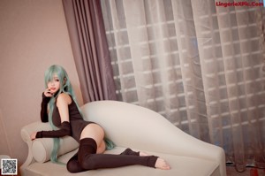 A woman with long green hair sitting on a couch.