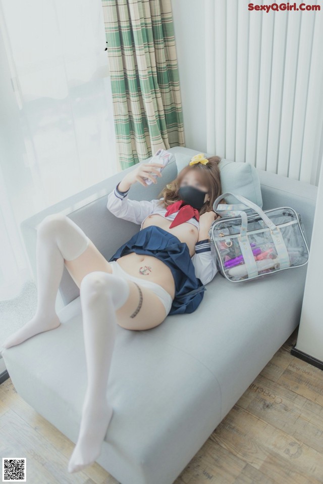 A woman laying on a couch with a cell phone in her hand.