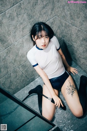 A woman in a white shirt and black shorts posing in a bathroom.