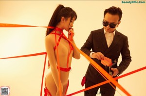 A woman in a red bikini and a man in a white coat.