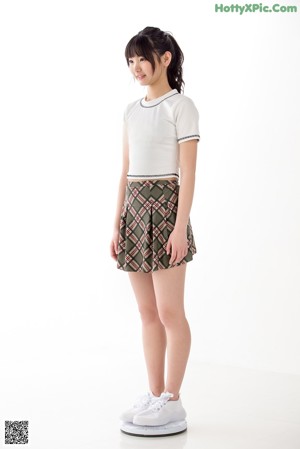 A woman in a white shirt and a plaid skirt.