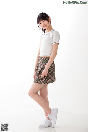 A young woman wearing a white shirt and plaid skirt.