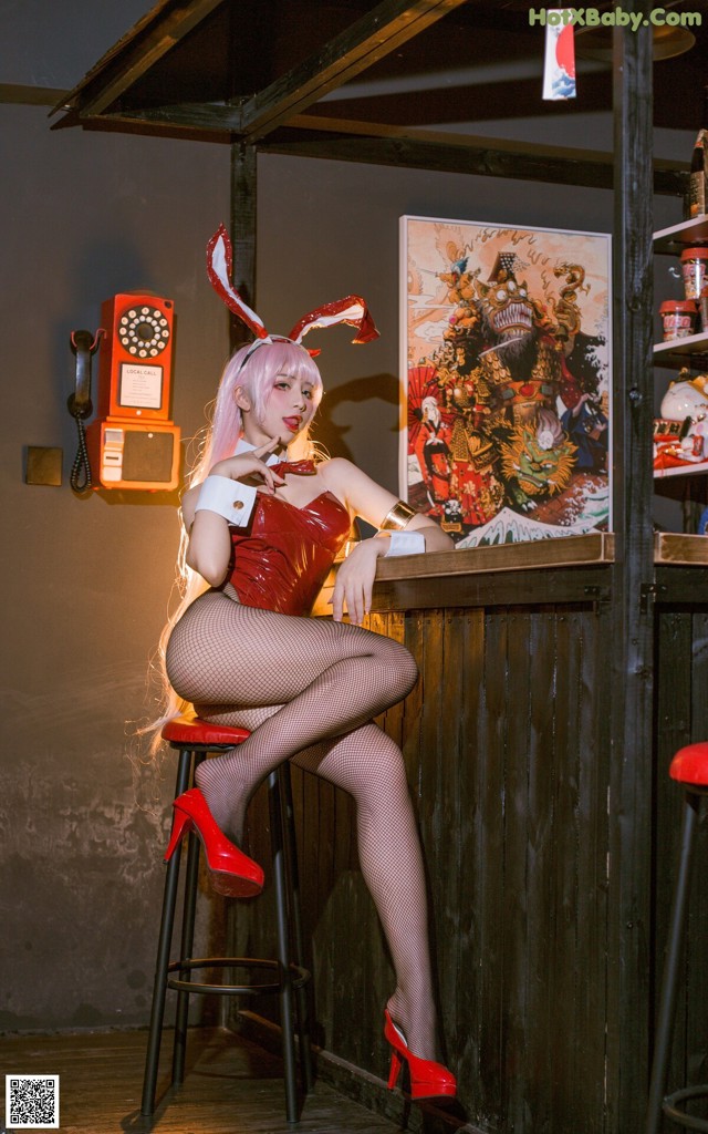 A woman in a bunny costume sitting at a bar.