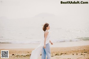 A woman standing on a beach with her arms outstretched.
