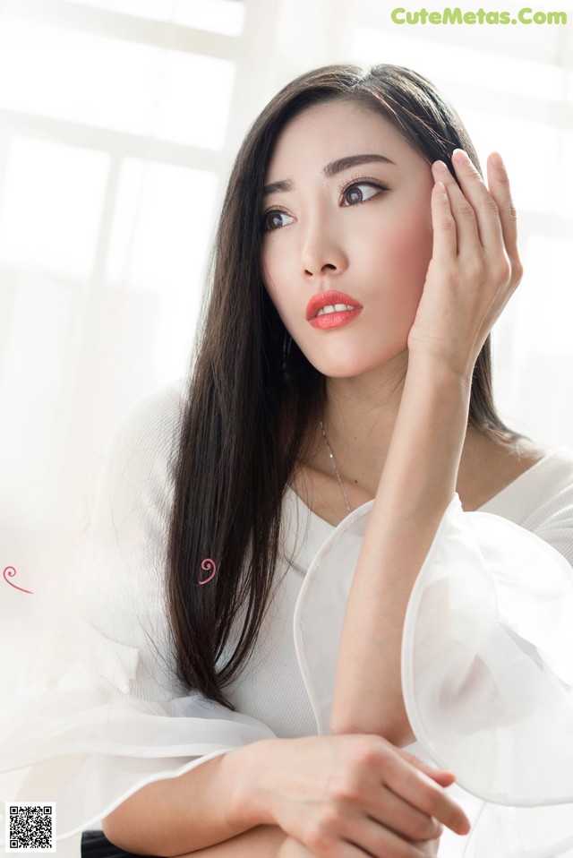 A woman in a white dress sitting on a chair.