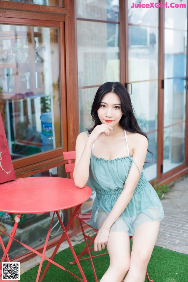 A woman sitting on a red chair in front of a building.