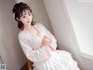 A woman in a white robe sitting on a window sill.