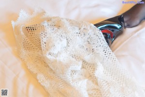 A woman in a white top and blue stockings posing on a bed.