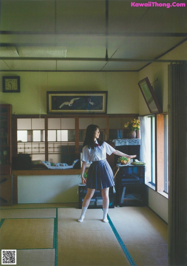 A woman in a school uniform standing in a room.