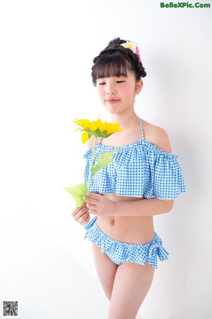 A young girl in a blue and white gingham bikini posing for a picture.