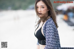 A woman walking on a beach with her back to the camera.