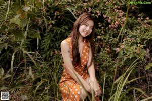 A woman in a polka dot dress standing in a field.