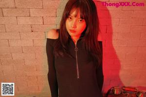 A woman in a black bodysuit sitting on the floor.
