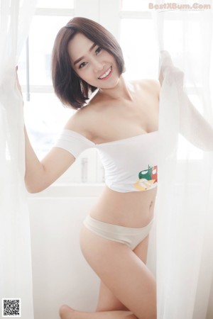 A woman in a white top and blue shorts posing for a picture.
