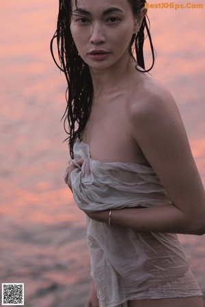 A woman in a black bikini standing by a window.