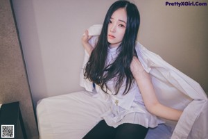 A woman in a white shirt and black stockings posing for a picture.