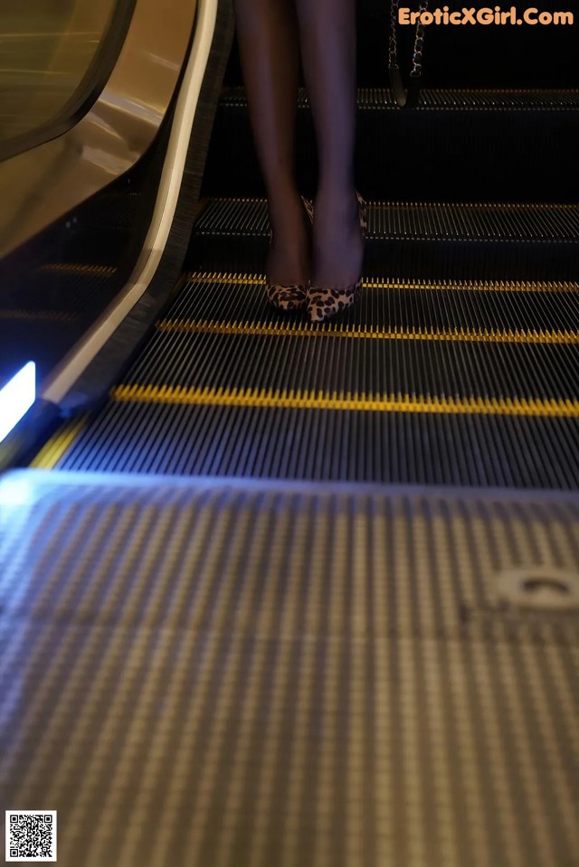 A woman is walking down an escalator with her legs up.