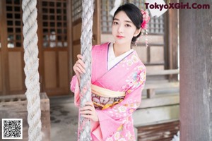 A woman in a pink kimono standing in the snow.