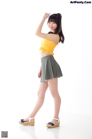 A woman in a yellow top and green skirt posing for a picture.