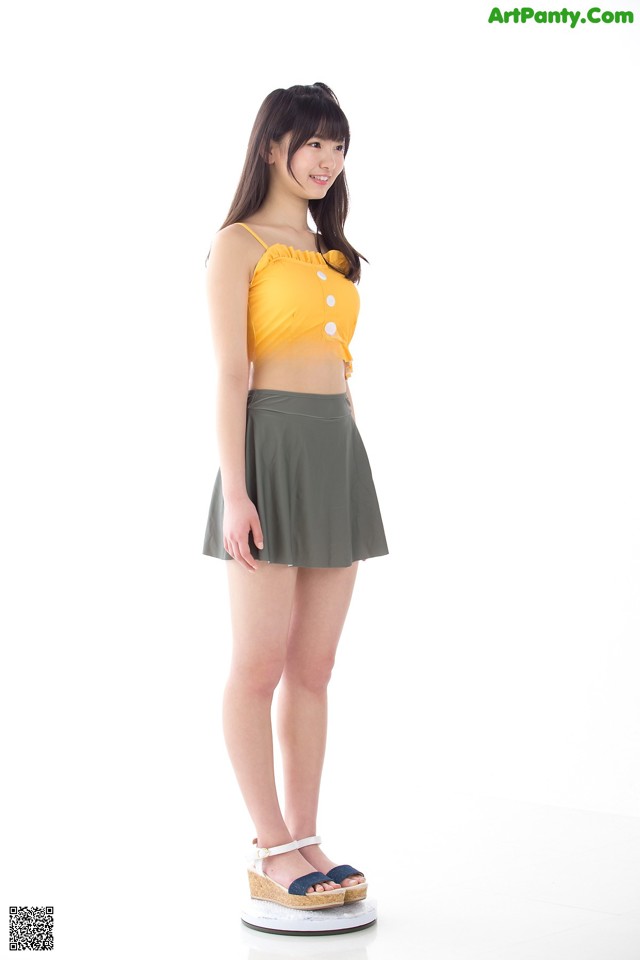 A woman in a yellow top and a green skirt.