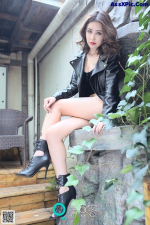 A woman sitting in a bathtub wearing a black bra and red shorts.