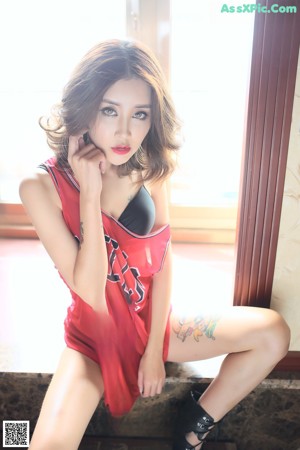 A woman sitting in a bathtub holding a red towel.