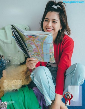 A woman with long black hair is looking at a magazine page.