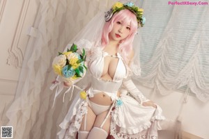 A woman with pink hair wearing a white dress and a flower crown.