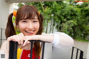 A young woman leaning against a metal gate.