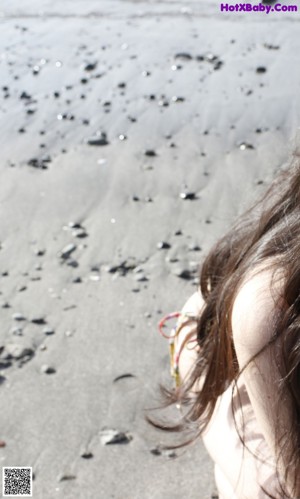 A woman in a bikini walking on the beach.